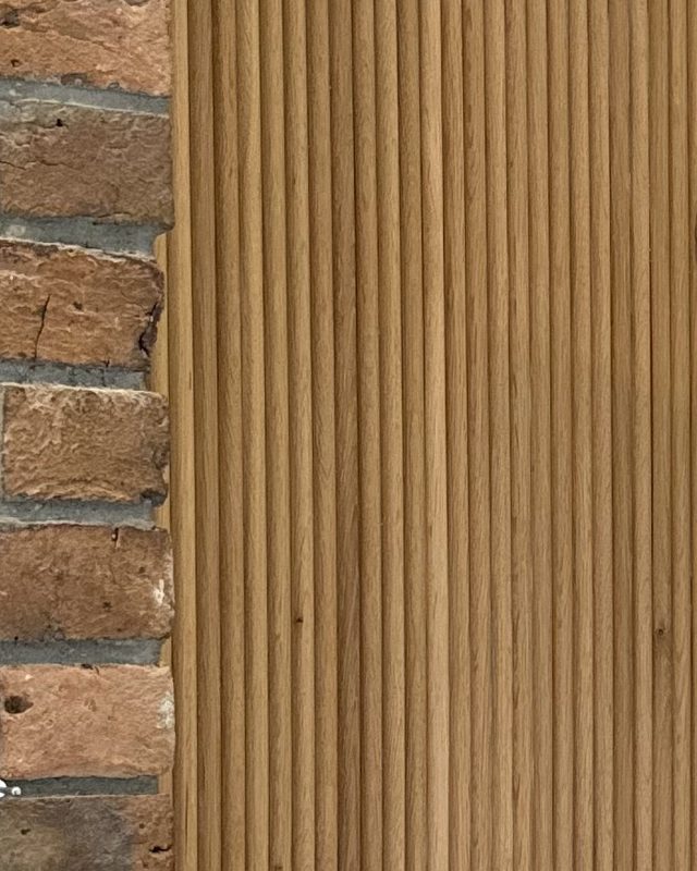 Oak slat panelling meeting a reclaimed brick pier